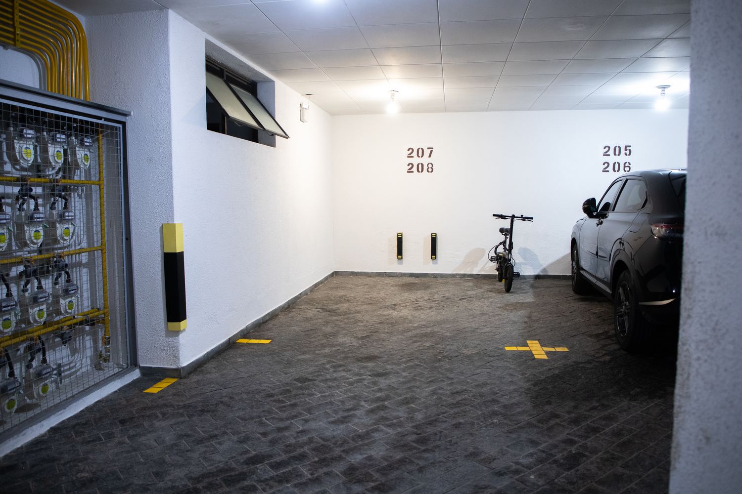 Garagem coberta do prédio com a vaga 207/208 identificada na parede