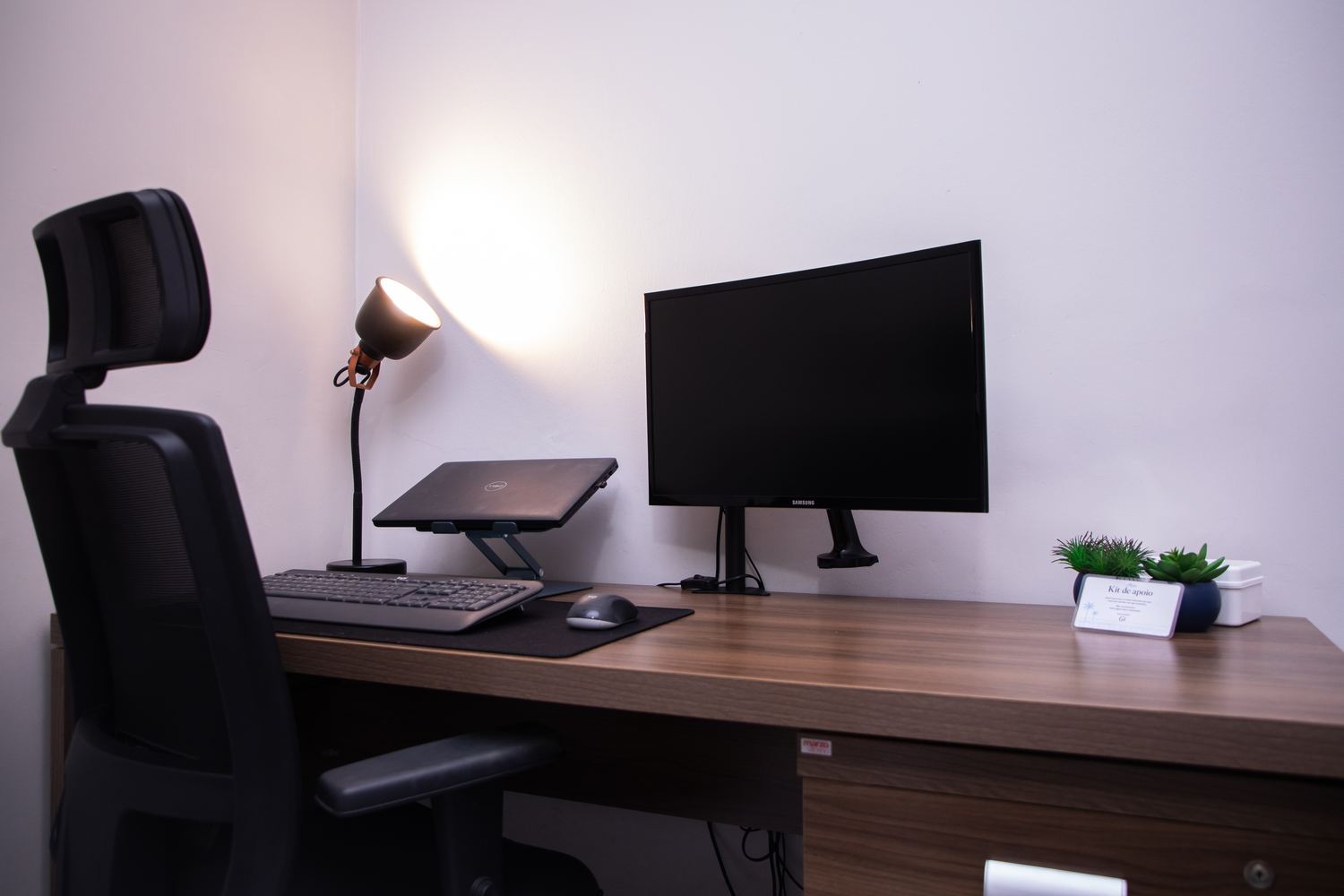 Home office com duas telas, cadeira de escritório e luminária